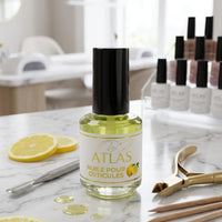 Flacon d'huile pour cuticules ATLAS parfum citron 15ml avec accessoires de manucure professionnels sur table en marbre.